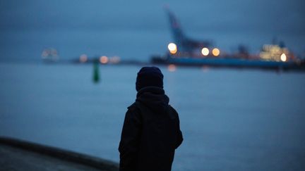 Siluett av person som tittar ut över Göteborgs hamn i skymning
